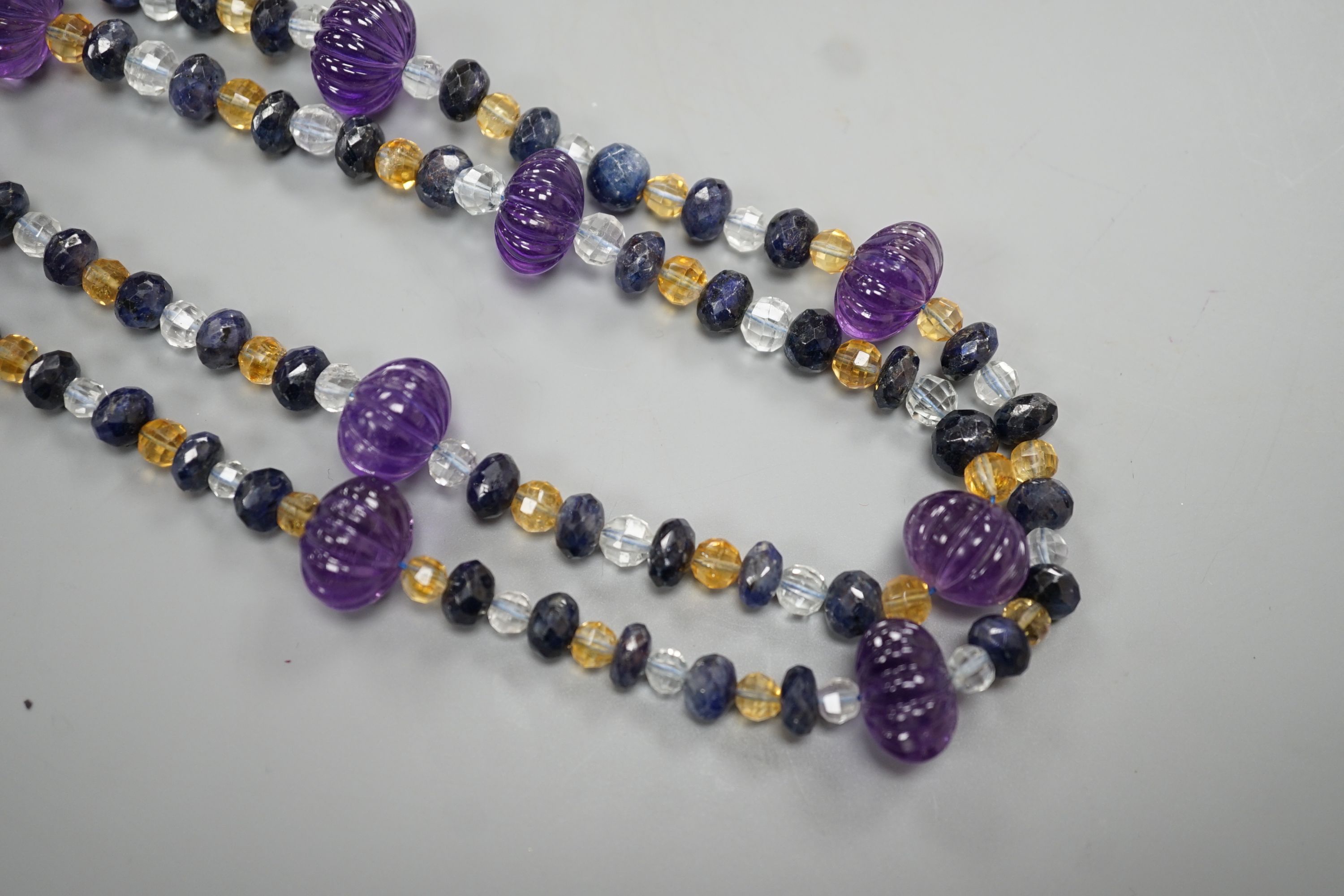 A modern single strand fluted amethyst and facet cut sapphire, citrine and aquamarine bead set necklace, 134cm.